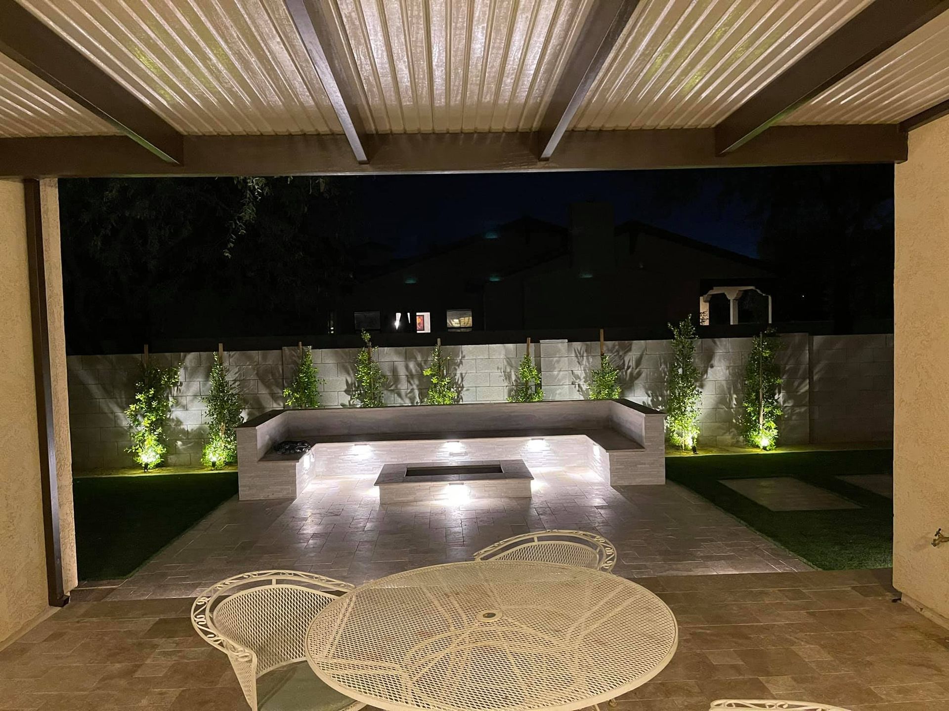 A patio with a fire pit and chairs at night.