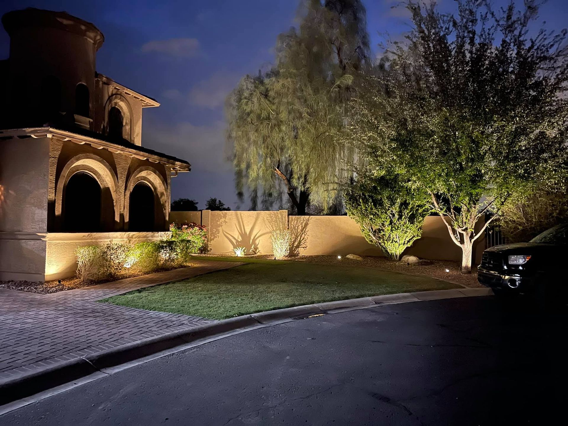 A house is lit up at night with a car parked in front of it.