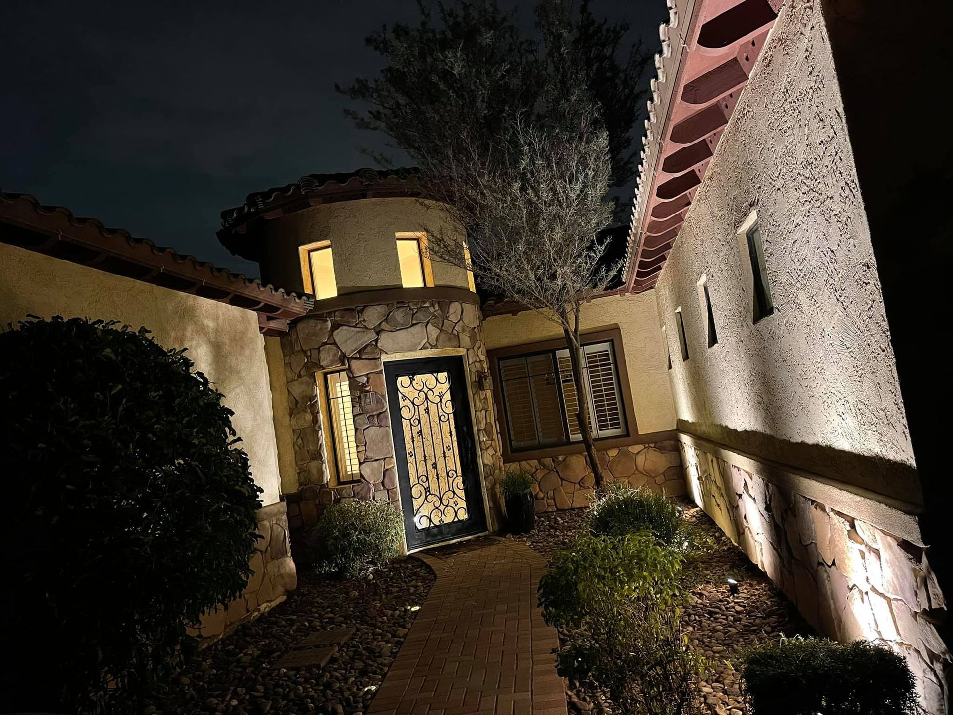 A brick walkway leading to a house at night