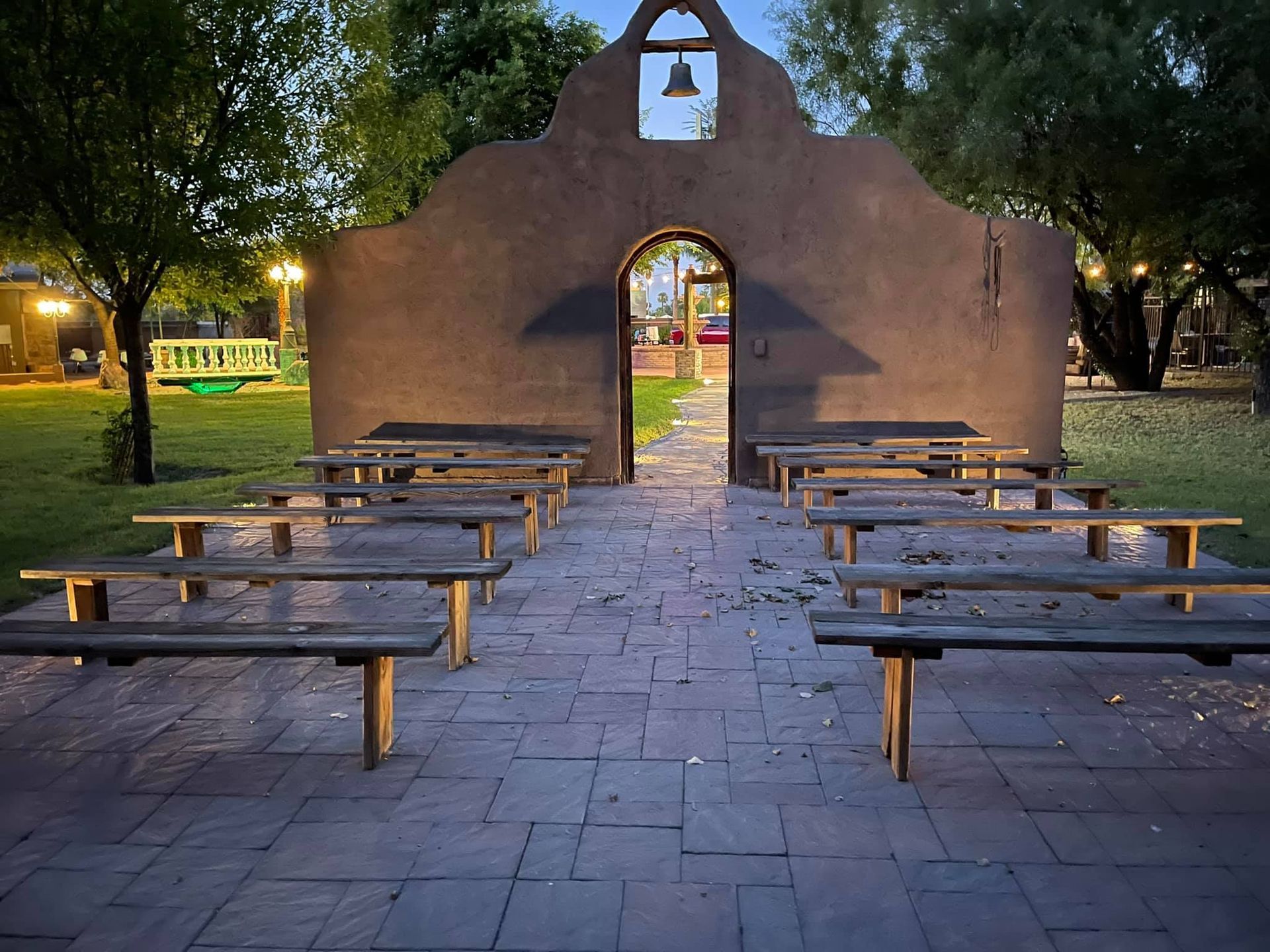 A row of wooden benches in front of a building with a bell on top.