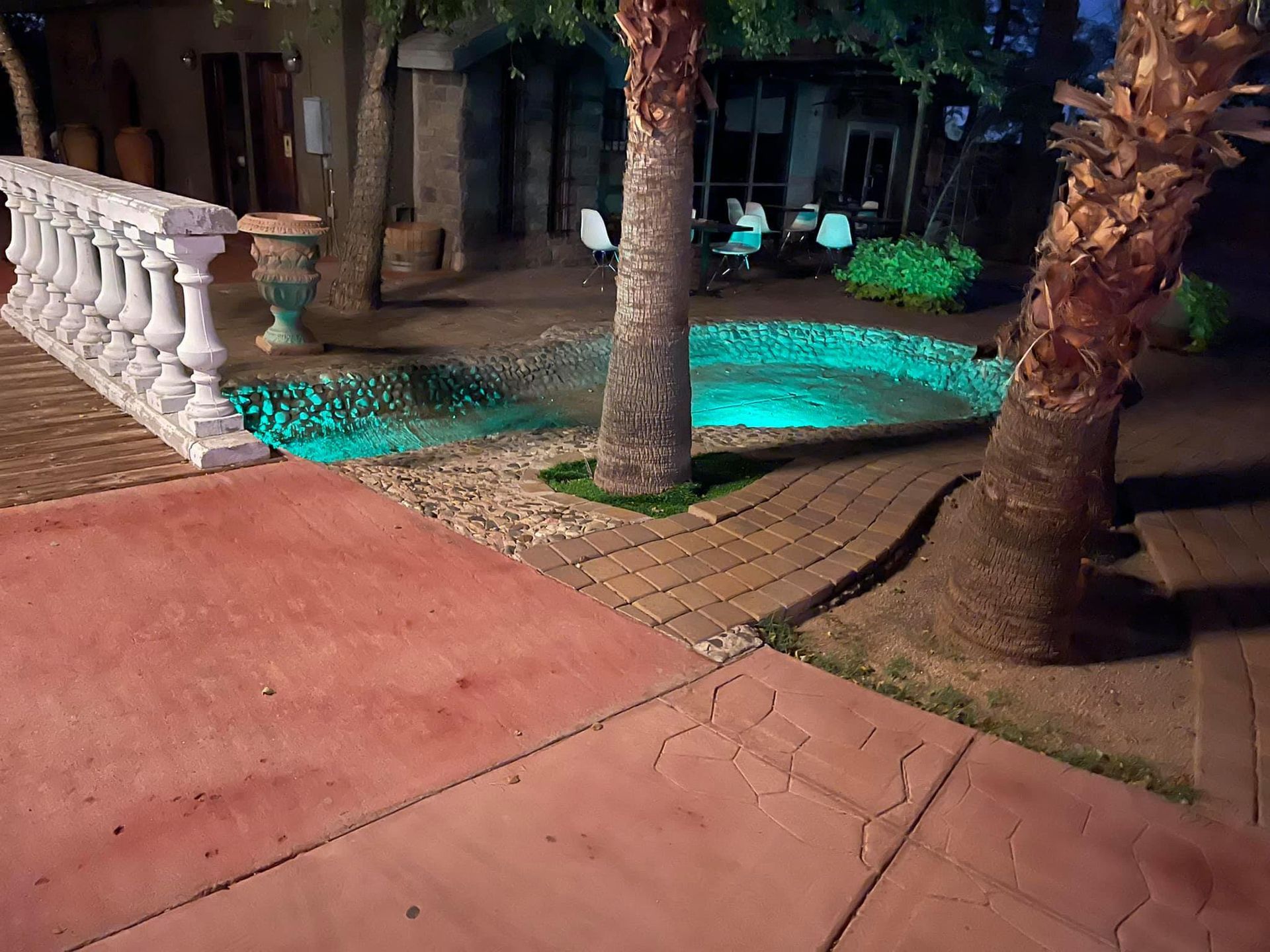 A swimming pool is lit up at night in a backyard