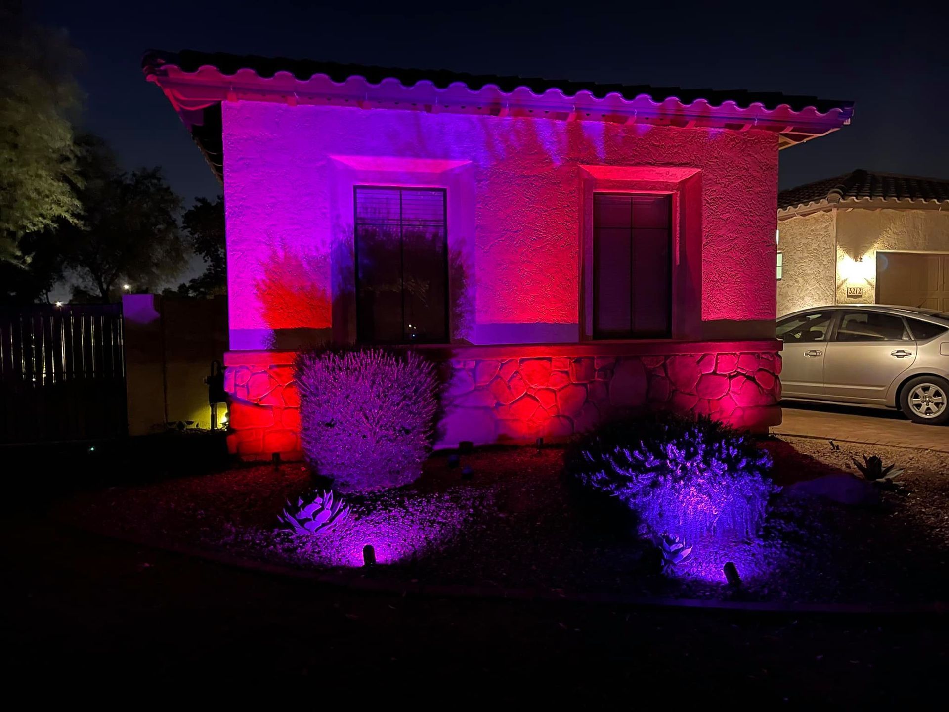 A house is lit up with purple and red lights at night.