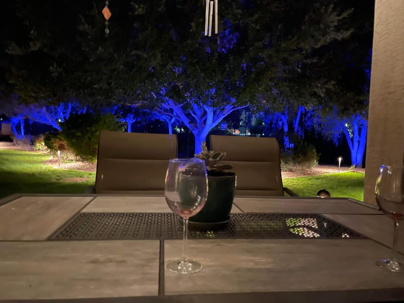 A glass of wine is sitting on a table outside at night.