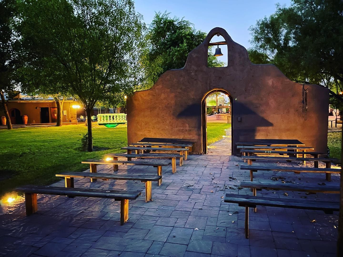 A row of benches in front of a building with a bell on top