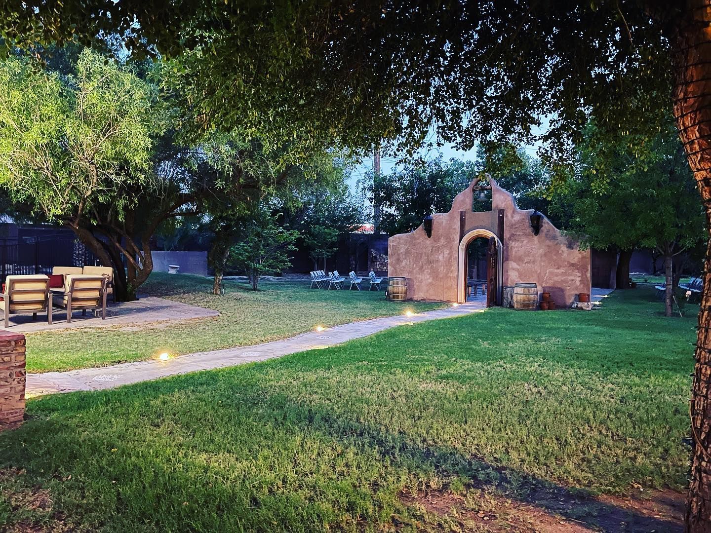 A brick building is surrounded by trees and grass in a park.