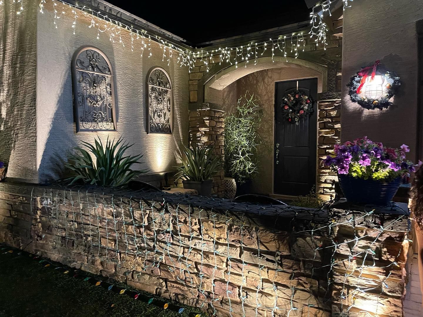 A house is decorated with christmas lights and flowers at night.