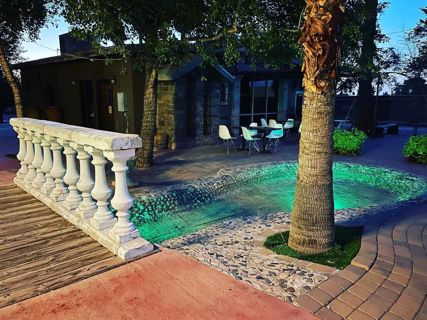 A swimming pool in front of a house with tables and chairs