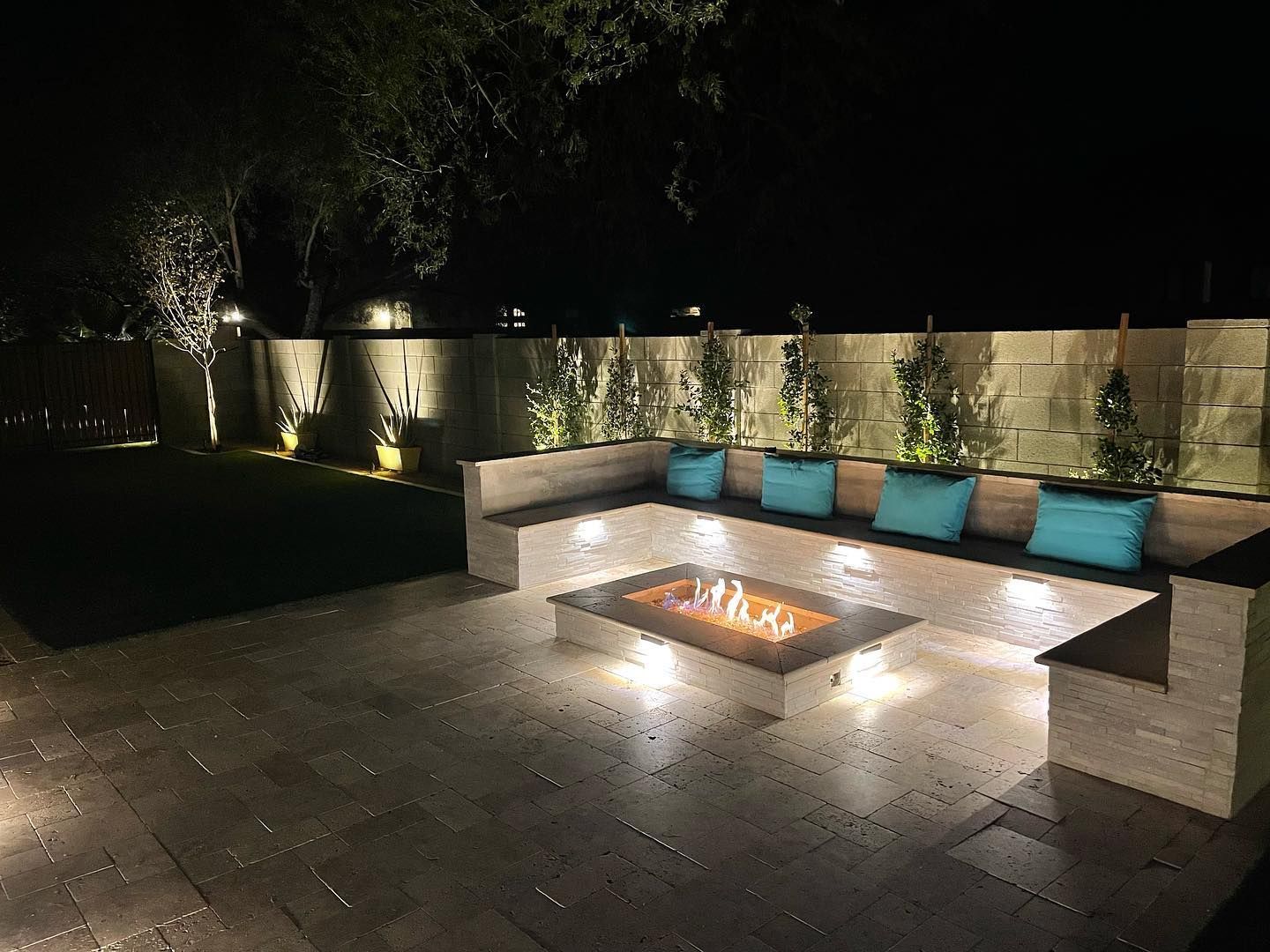 A patio with a fire pit and a couch at night.