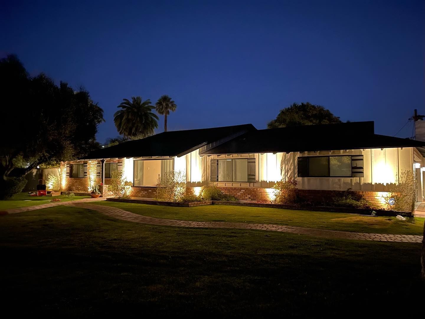 A house is lit up at night with palm trees in the background