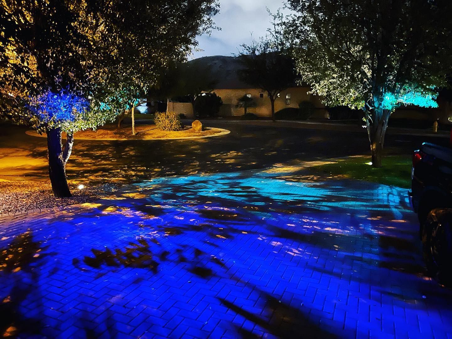 A car is parked in a driveway with blue lights on the ground