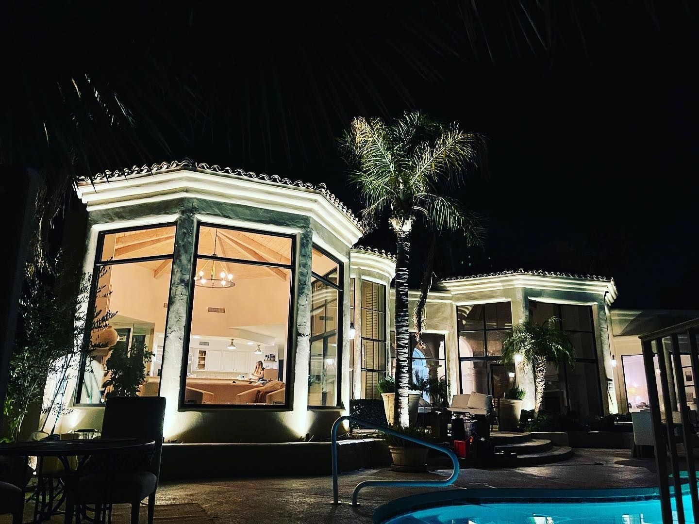 A house with a swimming pool in front of it at night.