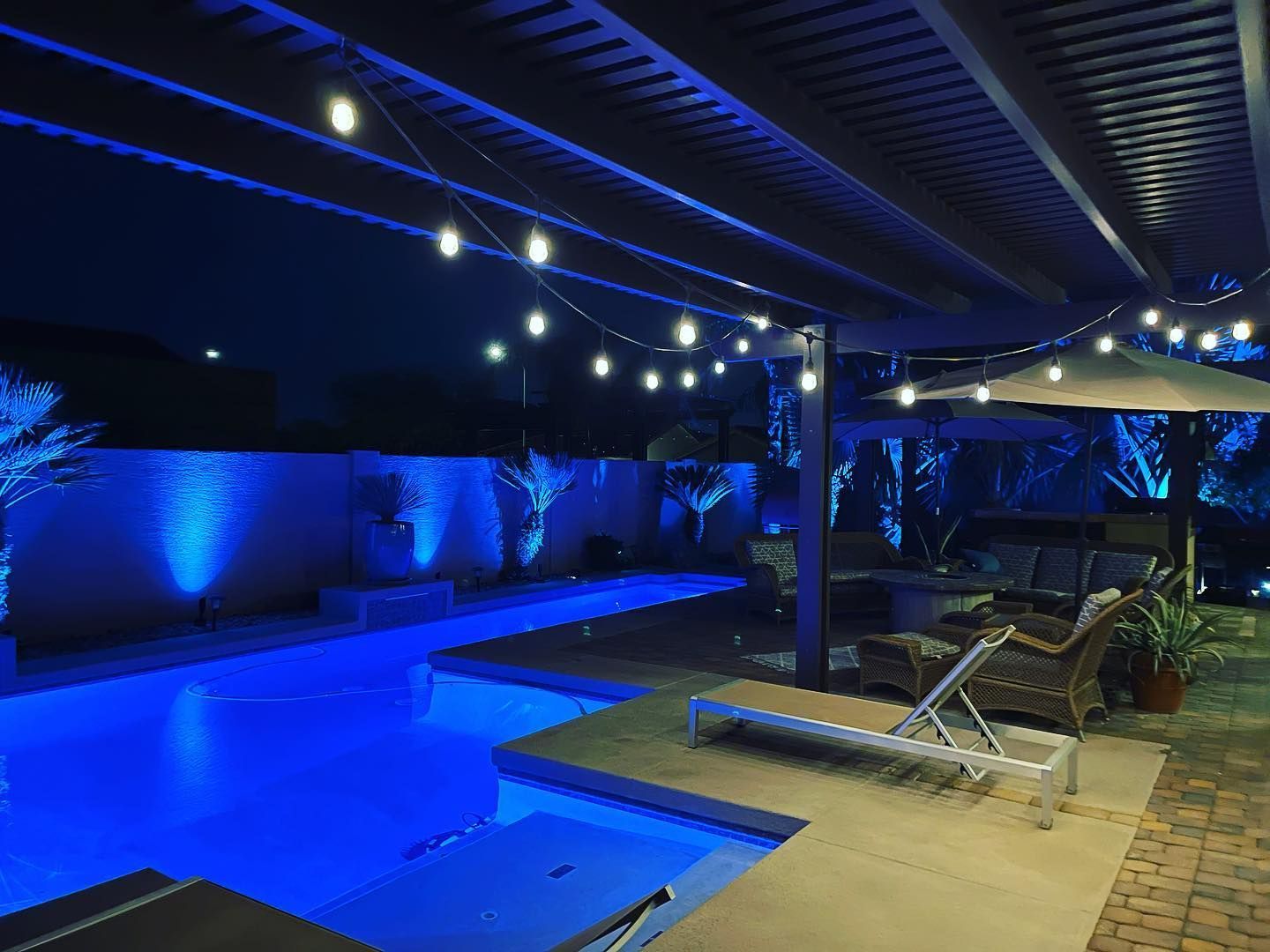 A large swimming pool is lit up at night with blue lights.