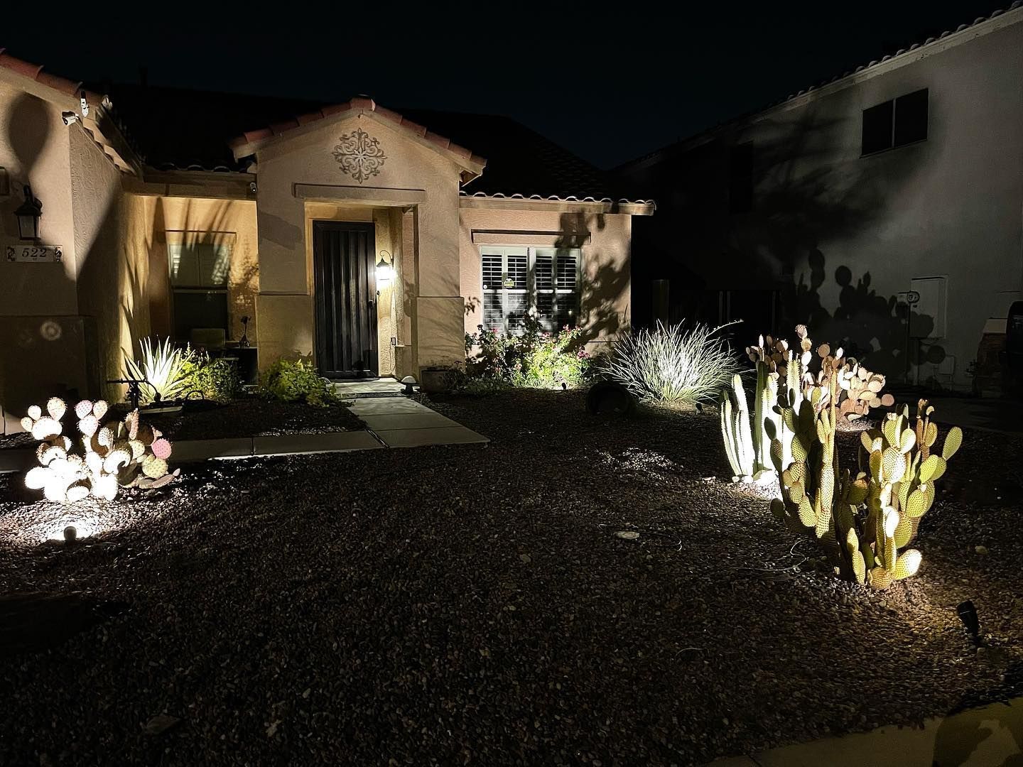 A house is lit up at night with cactus in front of it