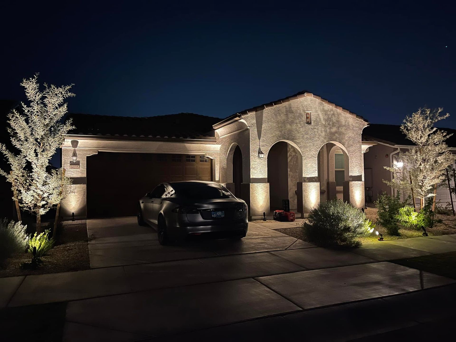 A car is parked in front of a house at night.