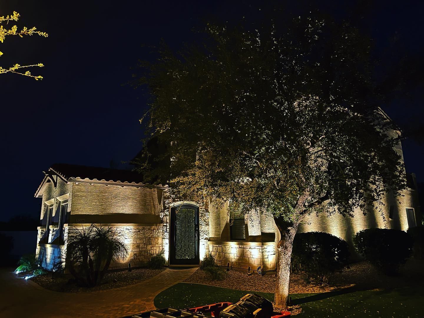 A house is lit up at night with trees in front of it
