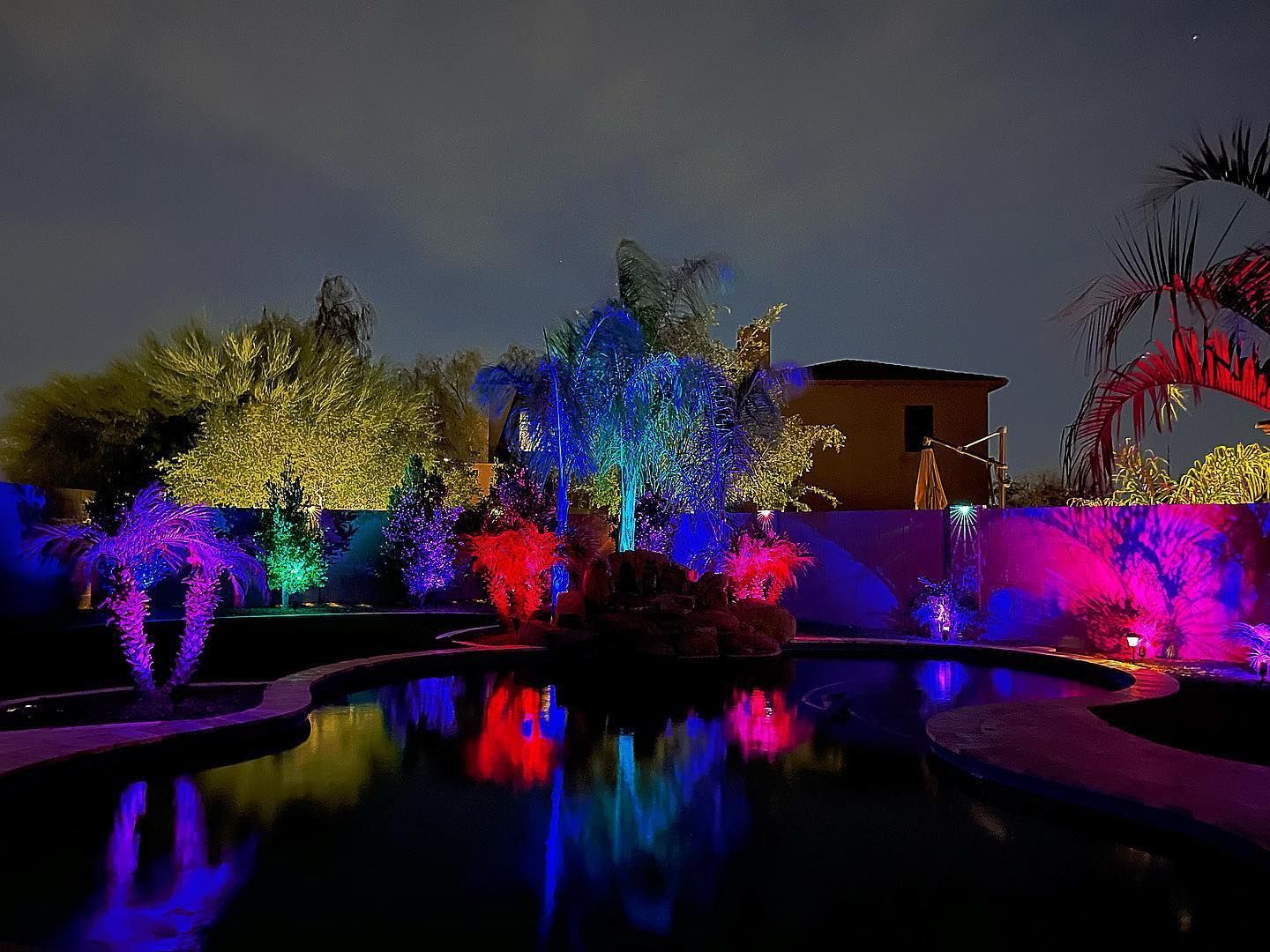 A swimming pool is lit up with colorful lights at night.