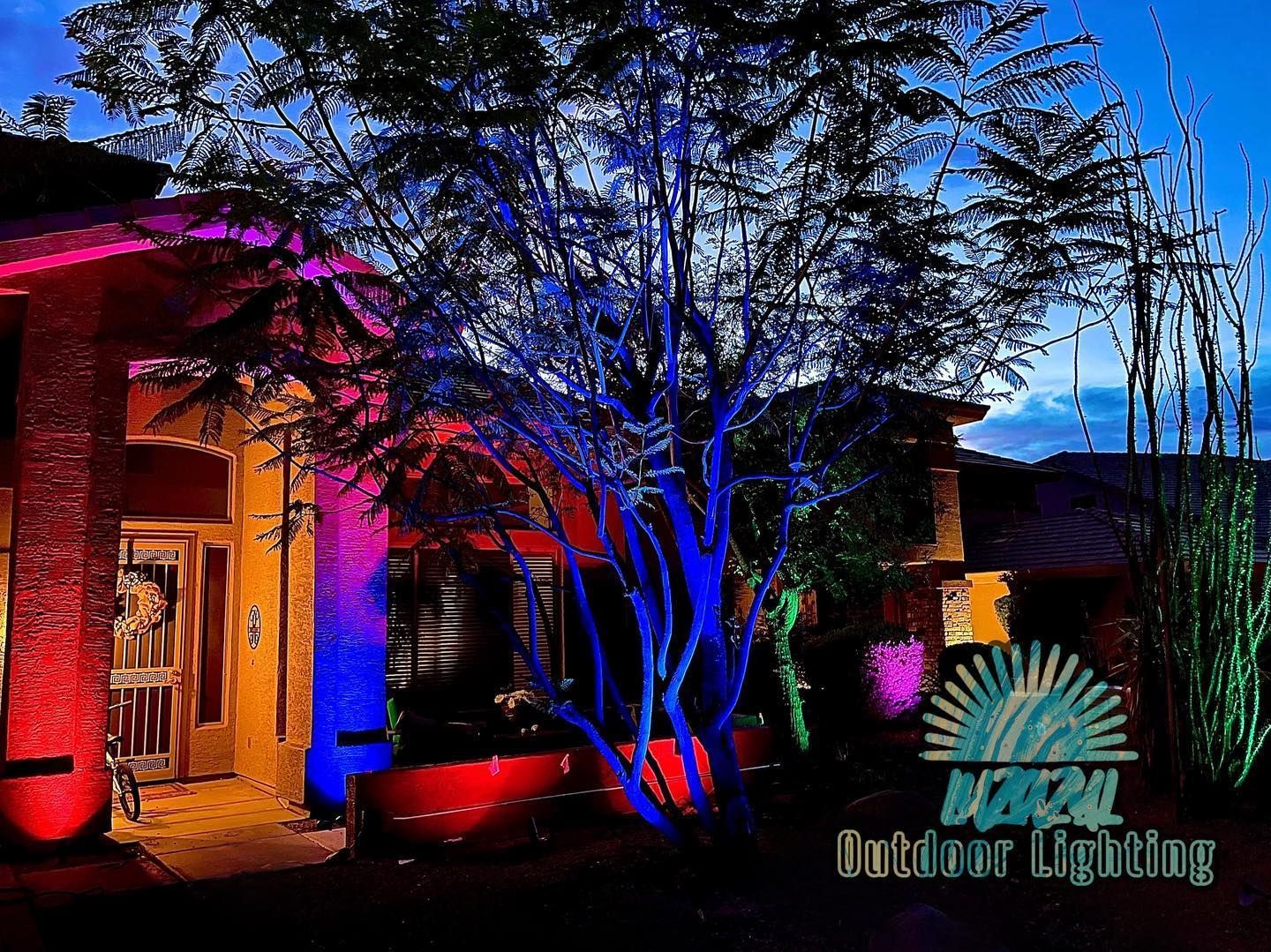 A picture of a house with trees lit up with colored lights