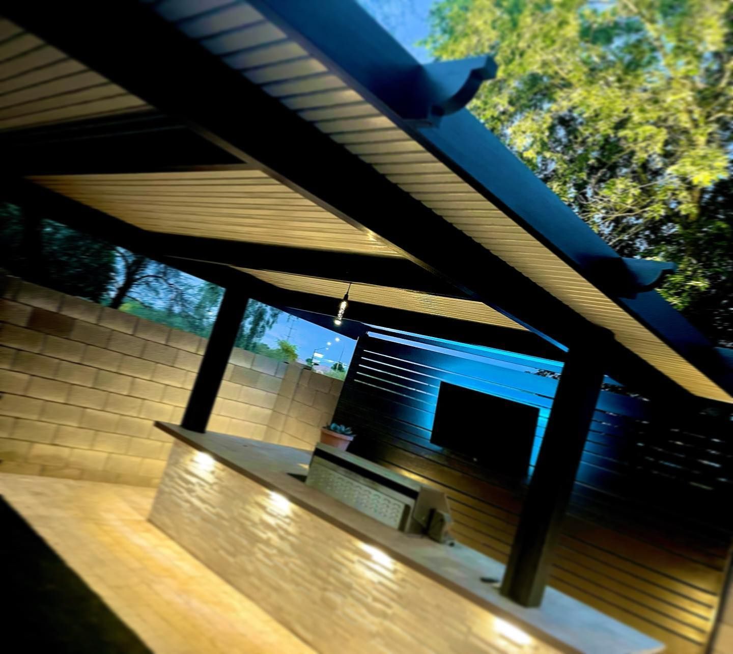 A covered area with a brick wall and trees in the background