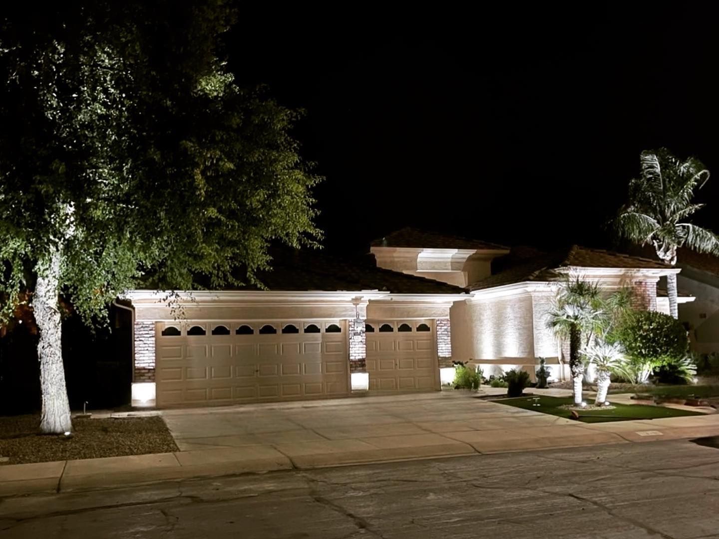 A house is lit up at night with trees in front of it