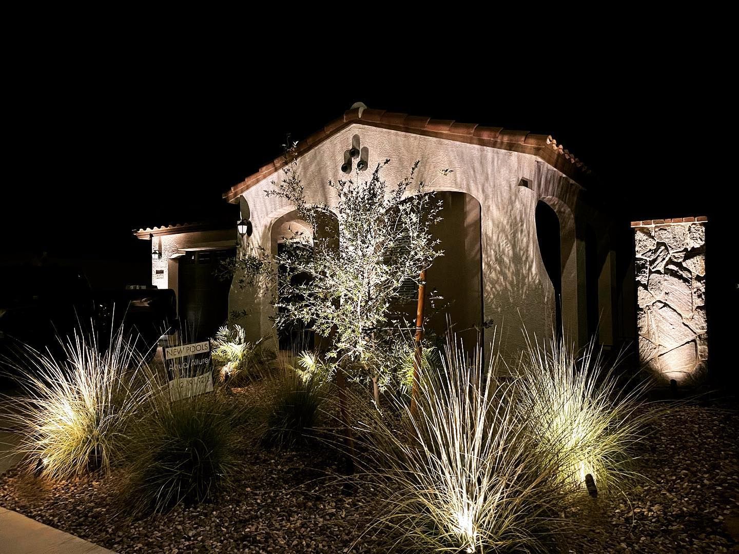 A house is lit up at night with lots of lights in front of it.