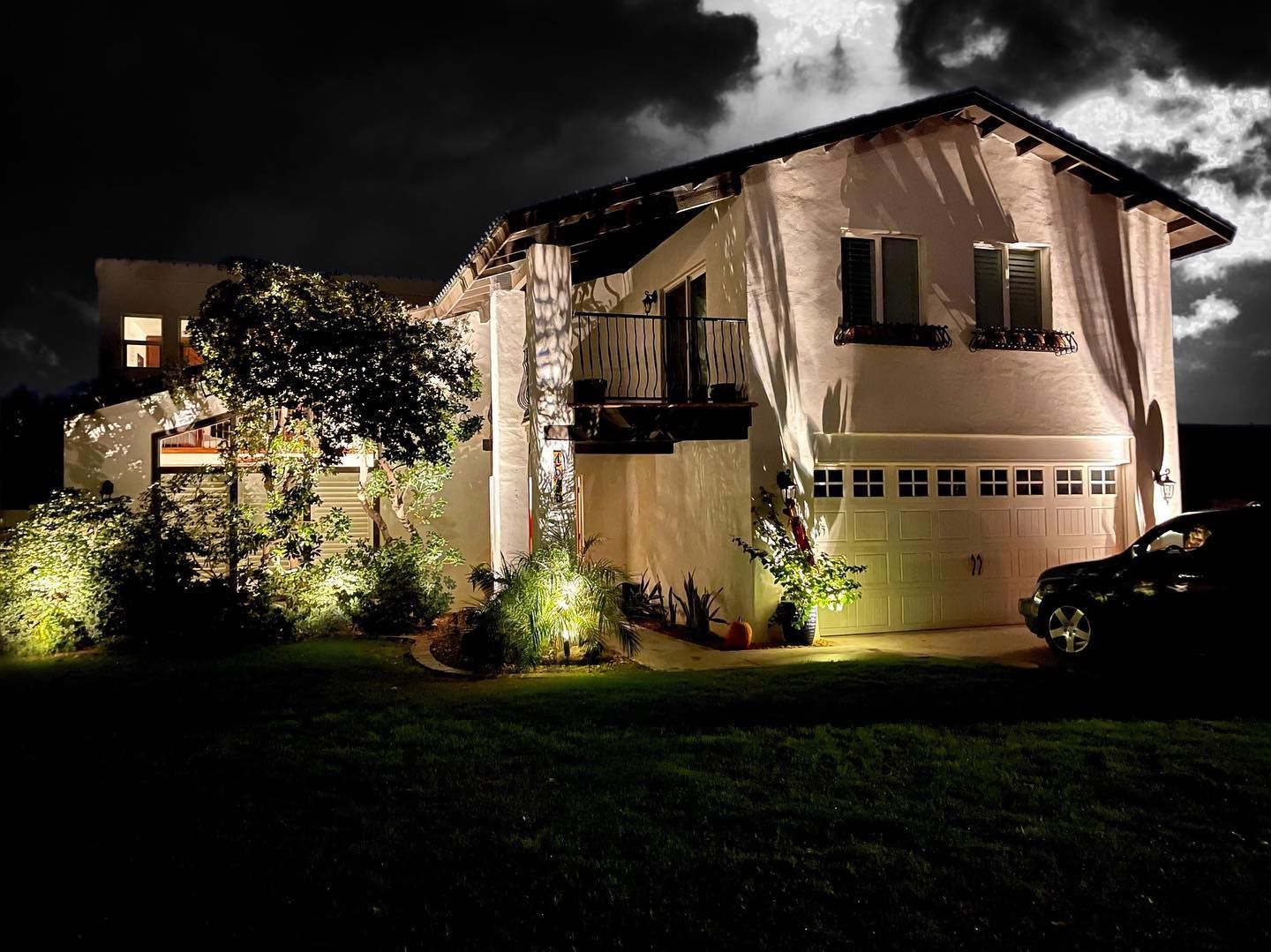 A house is lit up at night with a car parked in front of it