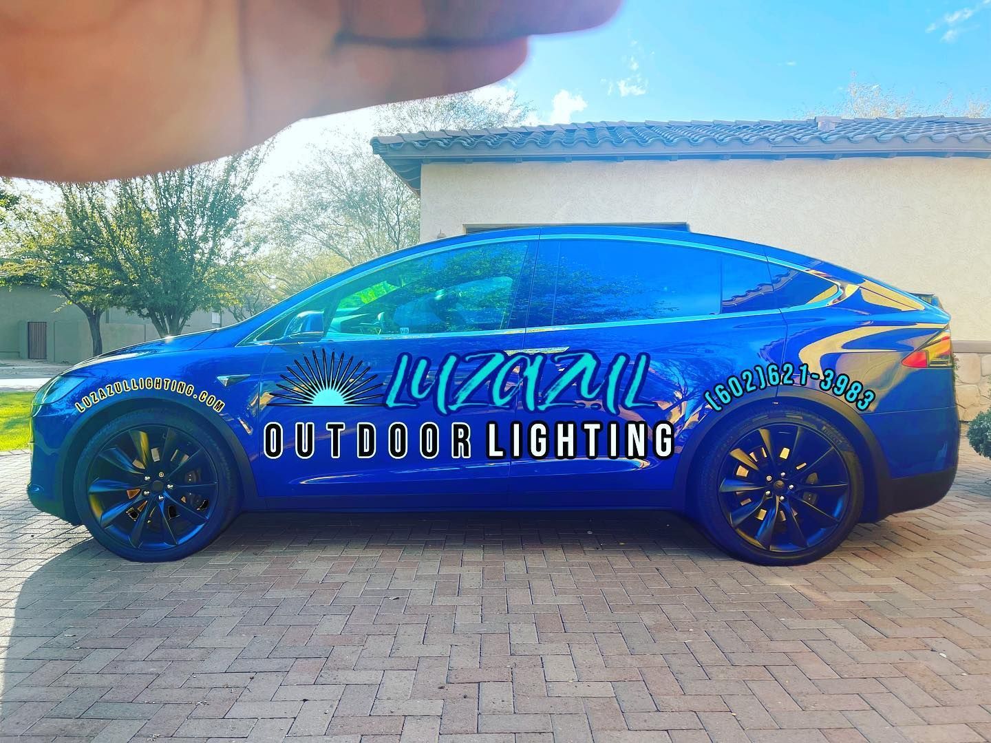 A blue car with the word outdoor lighting on the side