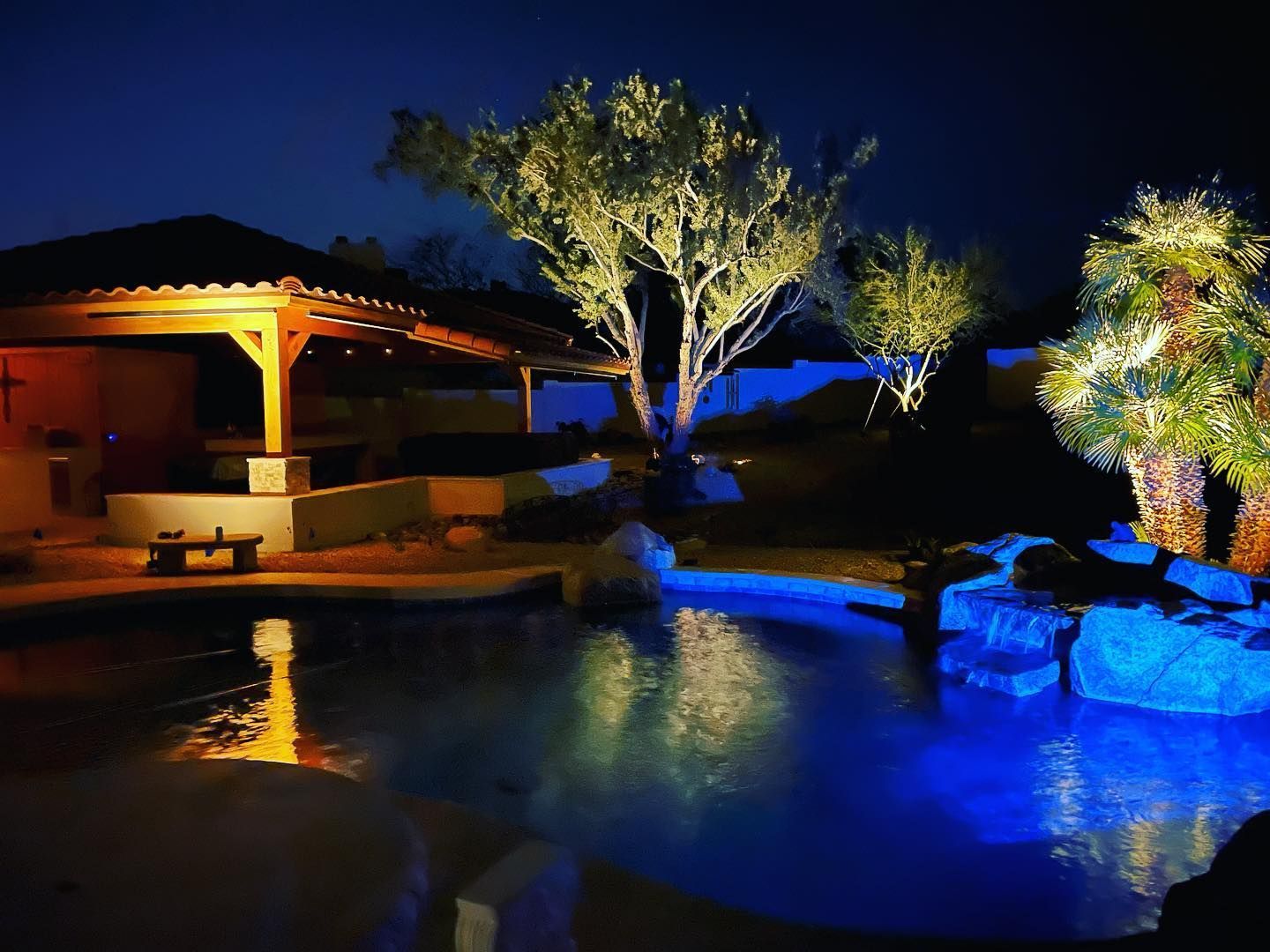 A swimming pool is lit up at night with blue lights