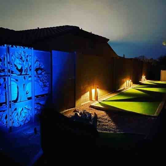 A house with a blue wall and a green lawn at night.