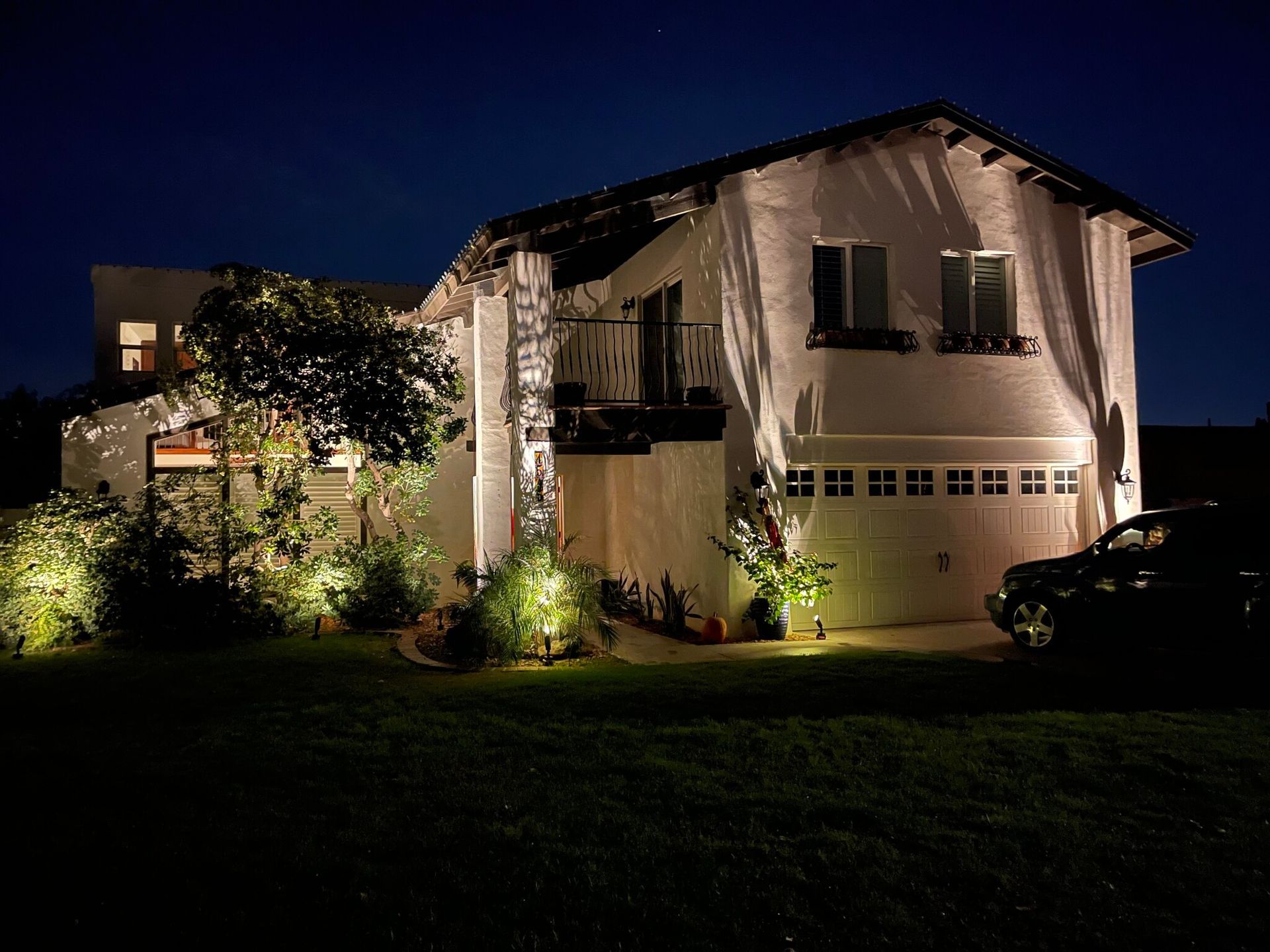 A house is lit up at night with a car parked in front of it