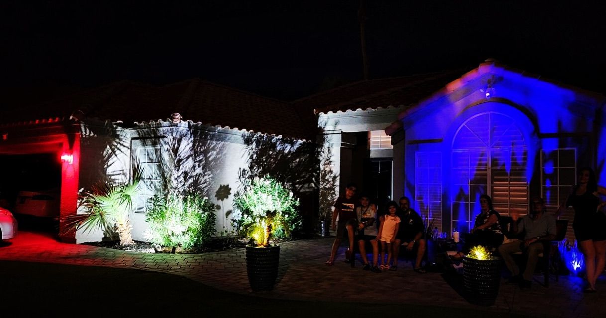 A group of people are sitting outside of a house at night.