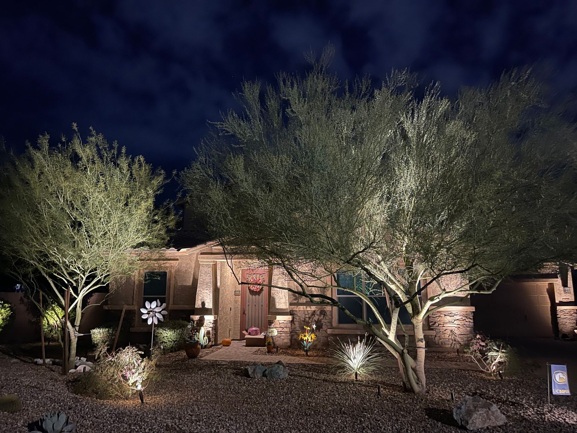 A house is lit up at night with trees in front of it.