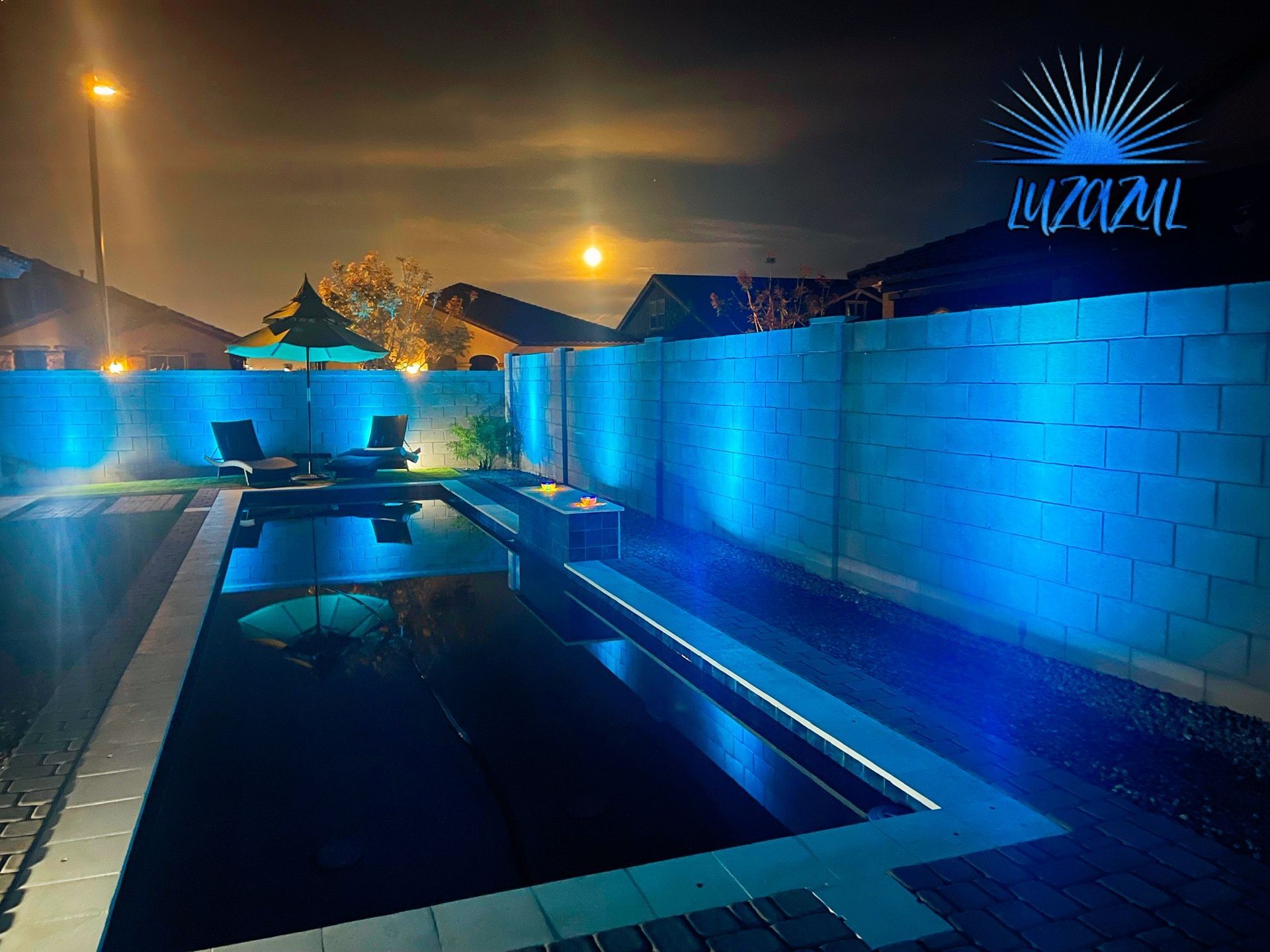 A swimming pool is lit up with blue lights at night