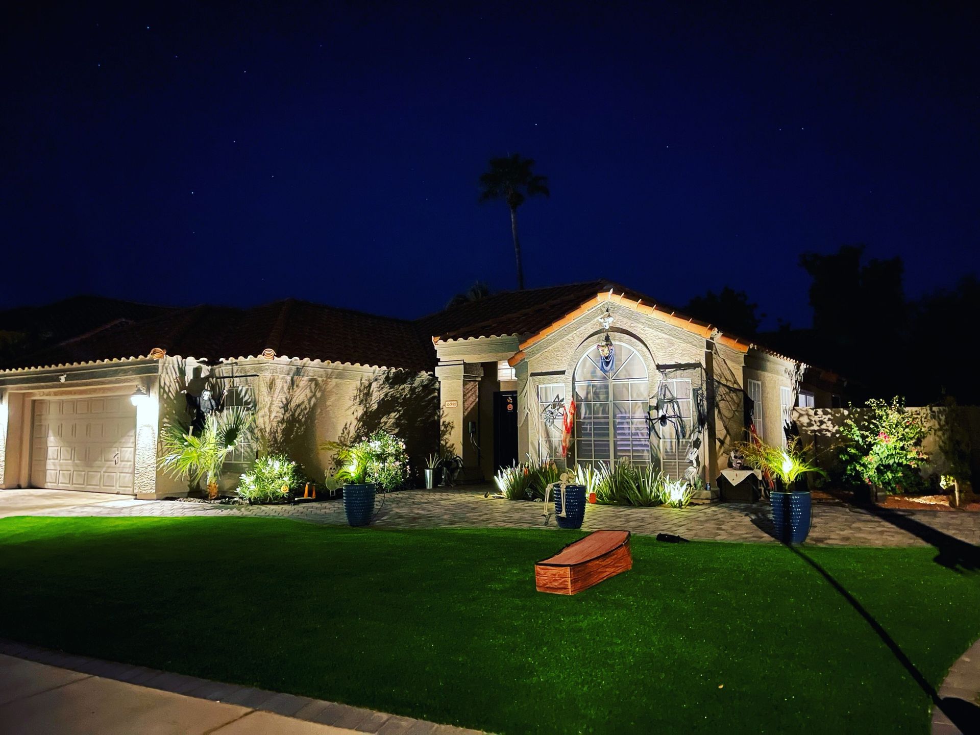 A house is lit up at night with a bench in front of it.