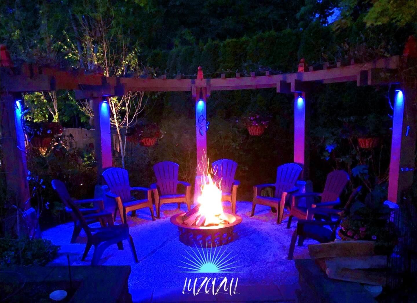 A fire pit is lit up with blue lights and surrounded by chairs