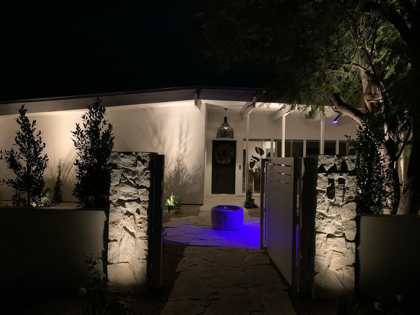 The front of a house is lit up at night with blue lights.