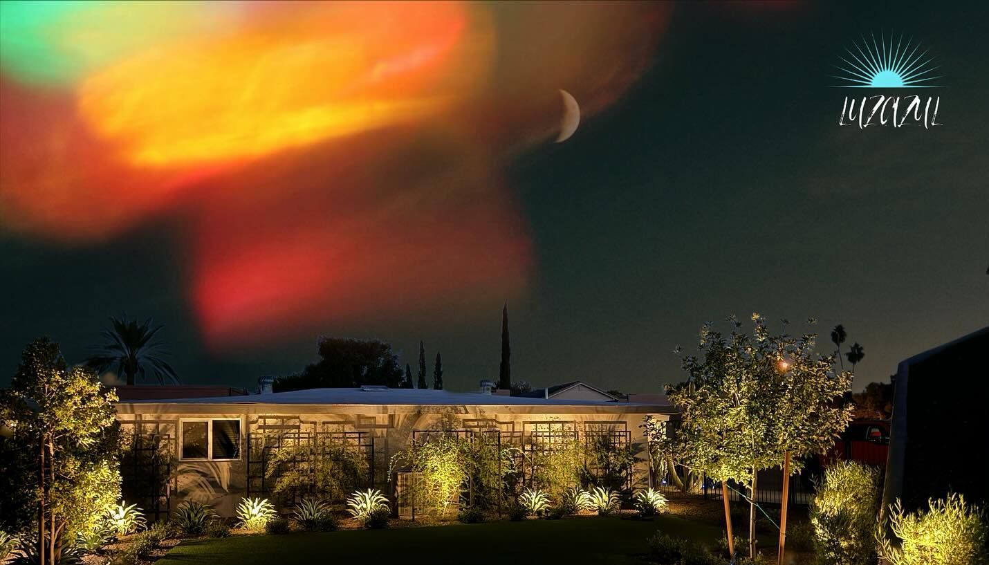 A house is lit up at night with a colorful sky in the background.