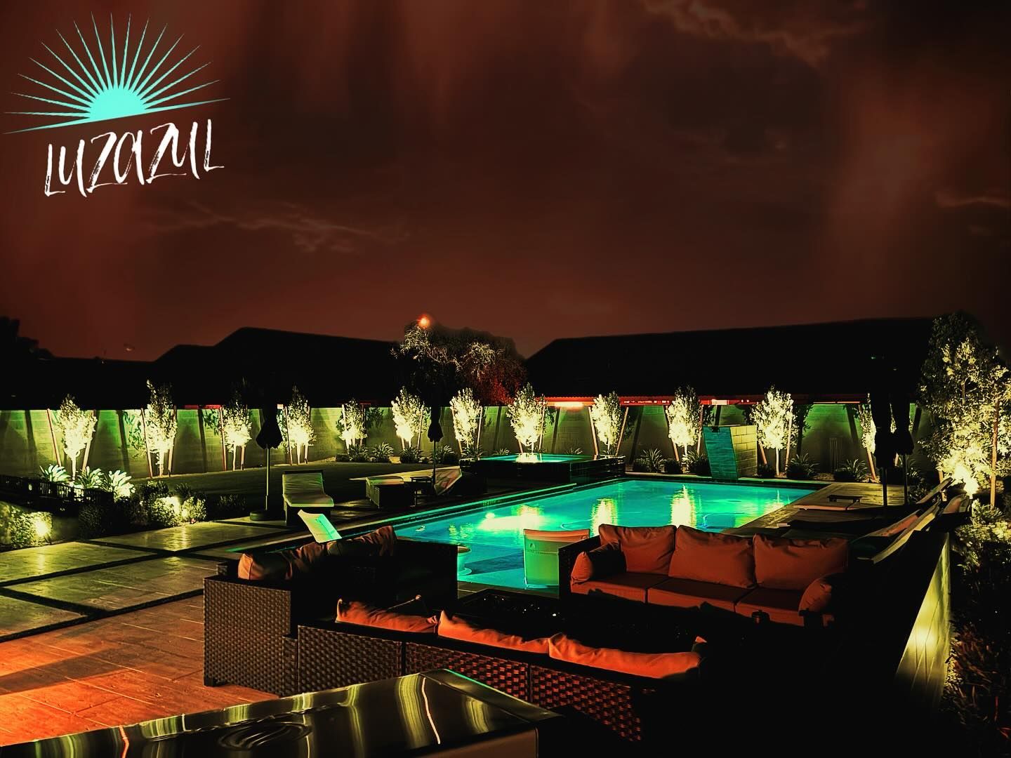 A large swimming pool is lit up at night with a sign that says luzoyal