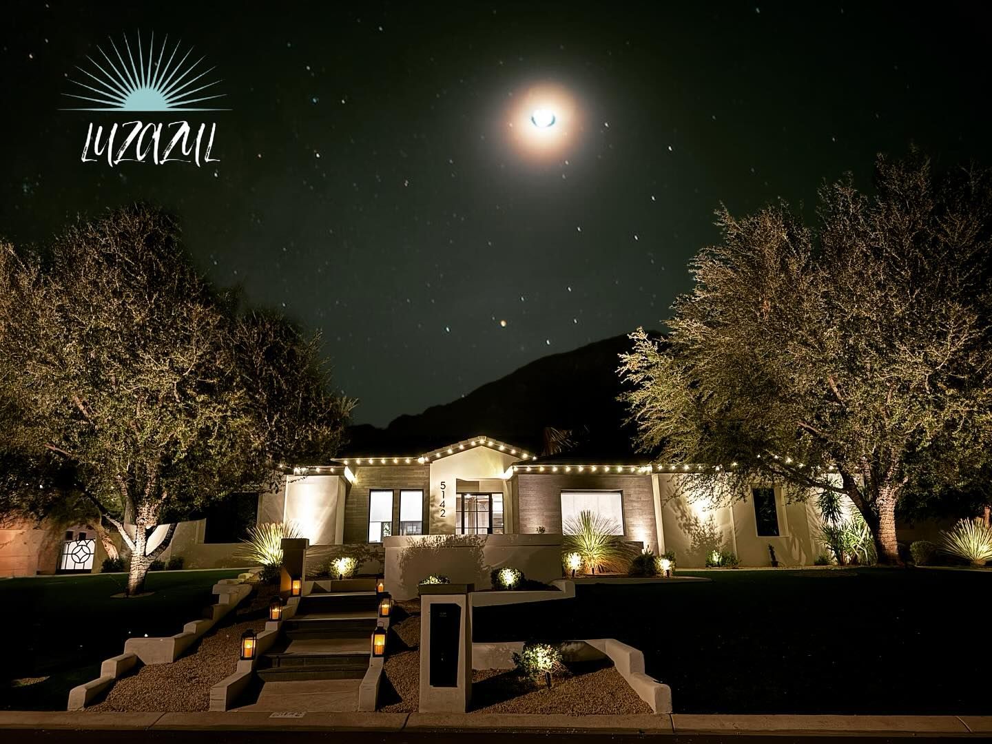 A house is lit up at night with a full moon in the sky