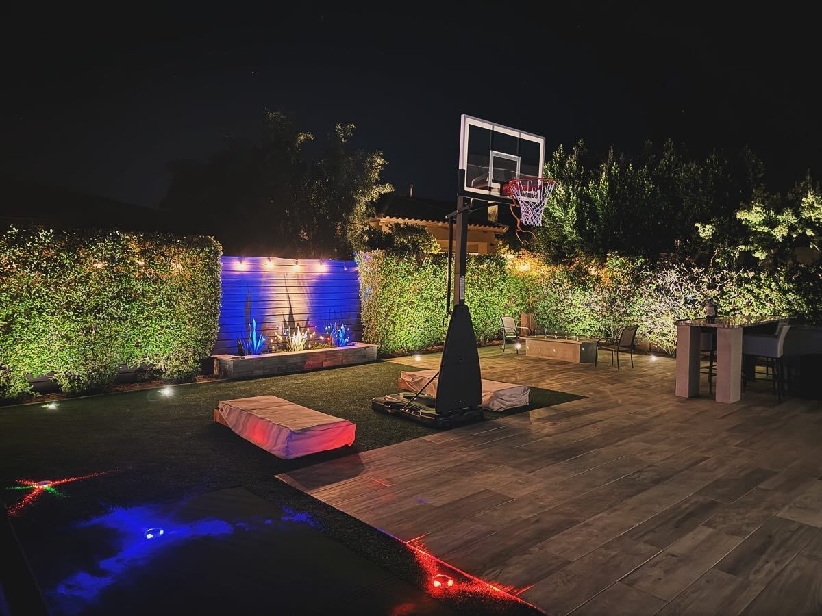 There is a basketball hoop in the backyard at night.