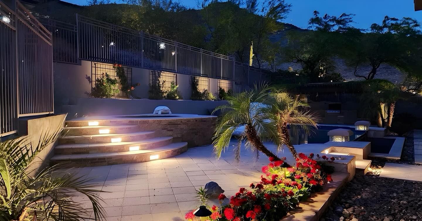 A patio with stairs and flowers is lit up at night.