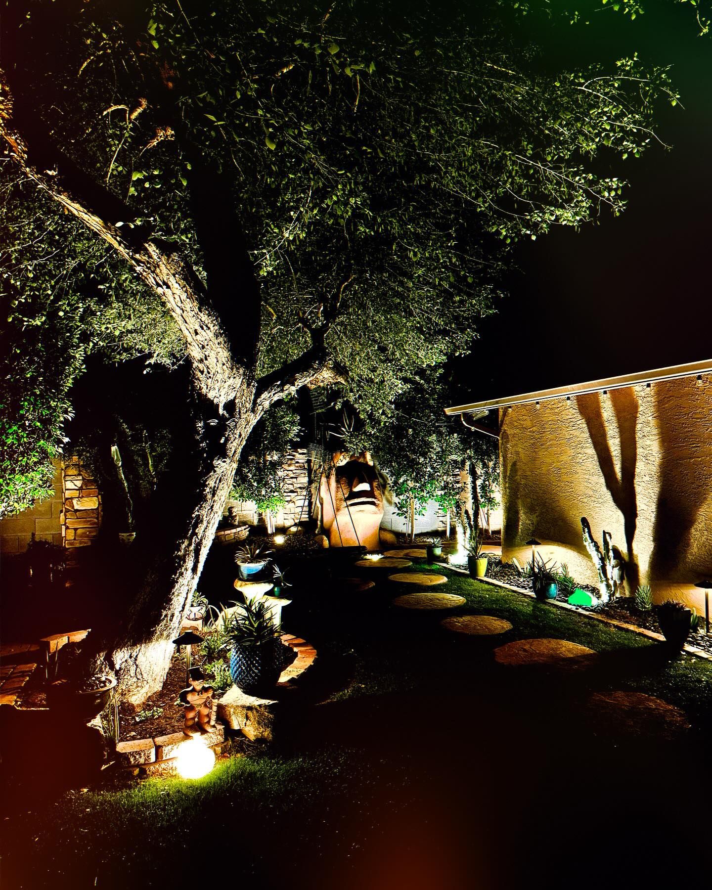 A house is lit up at night with a tree in the foreground