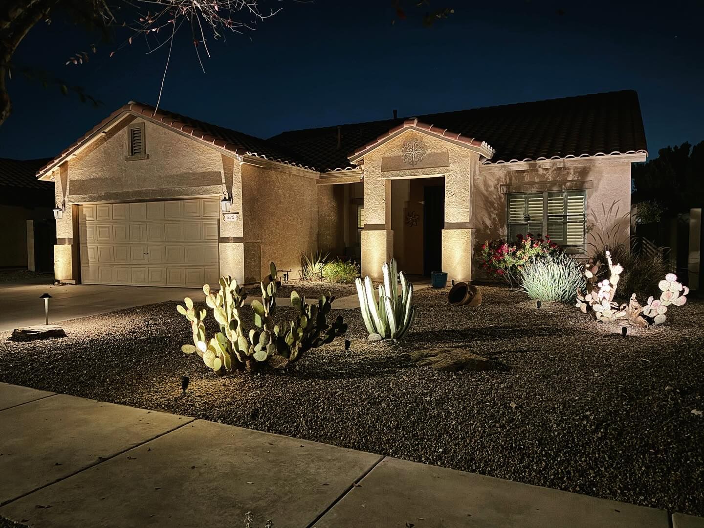 A house with a garage door is lit up at night.