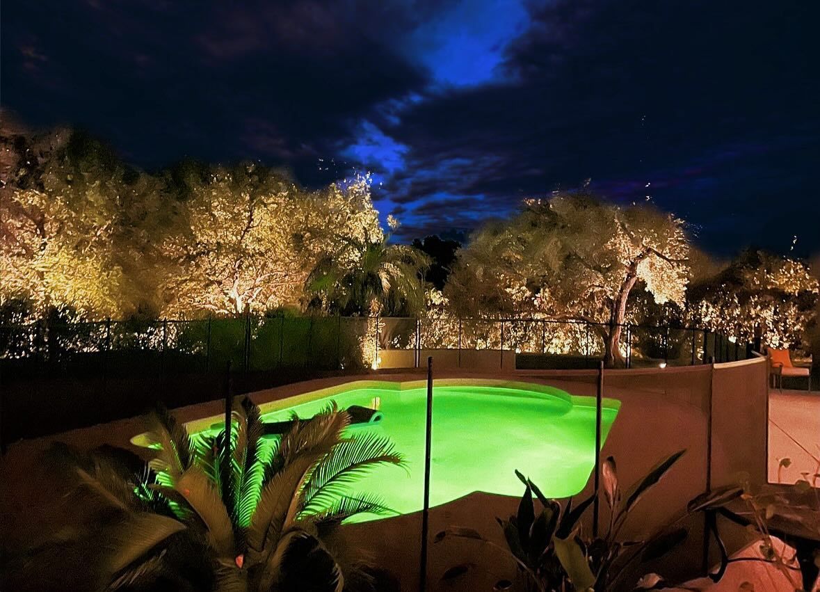 A swimming pool is lit up at night with green lights