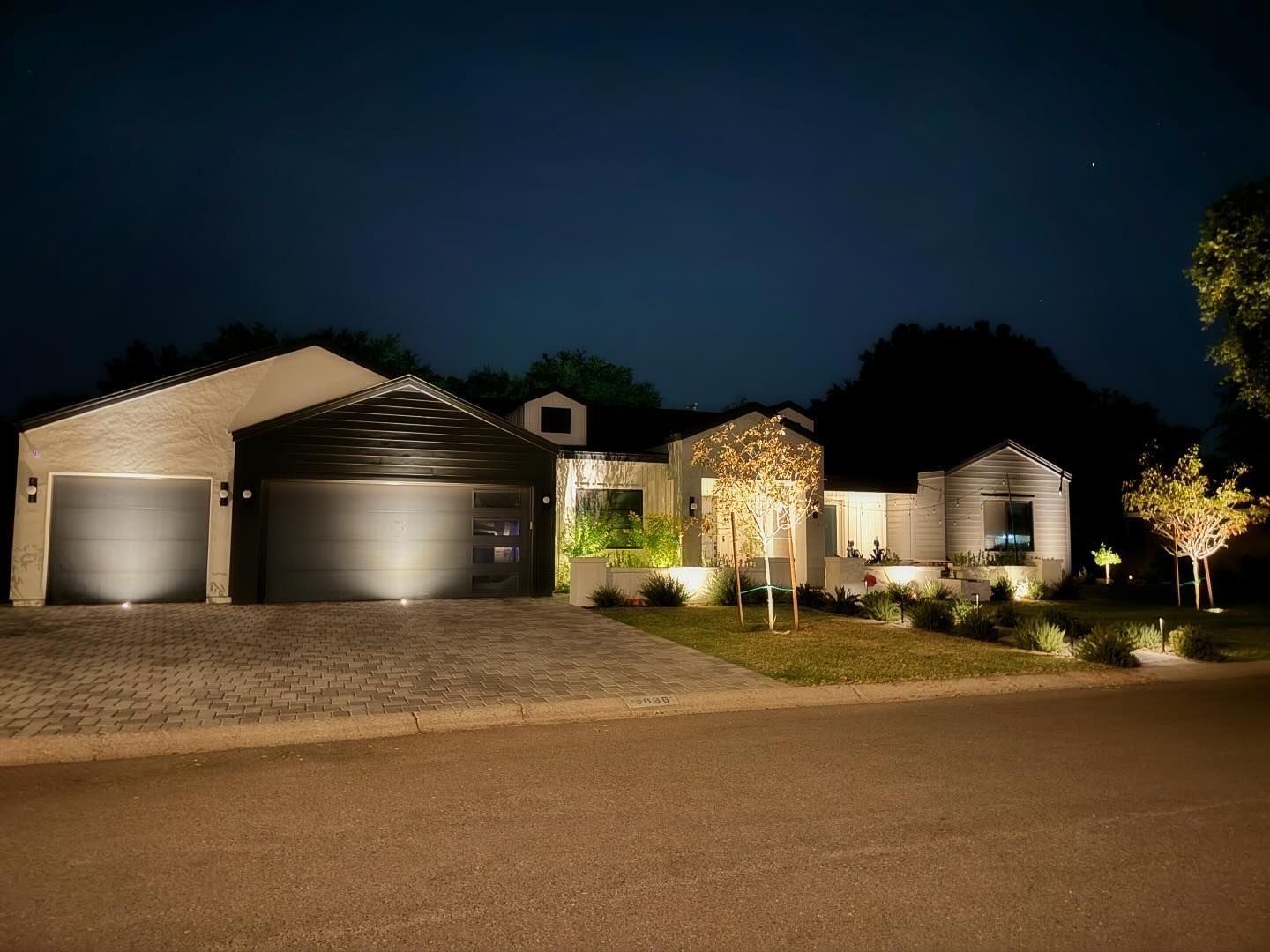 A house with two garage doors is lit up at night.