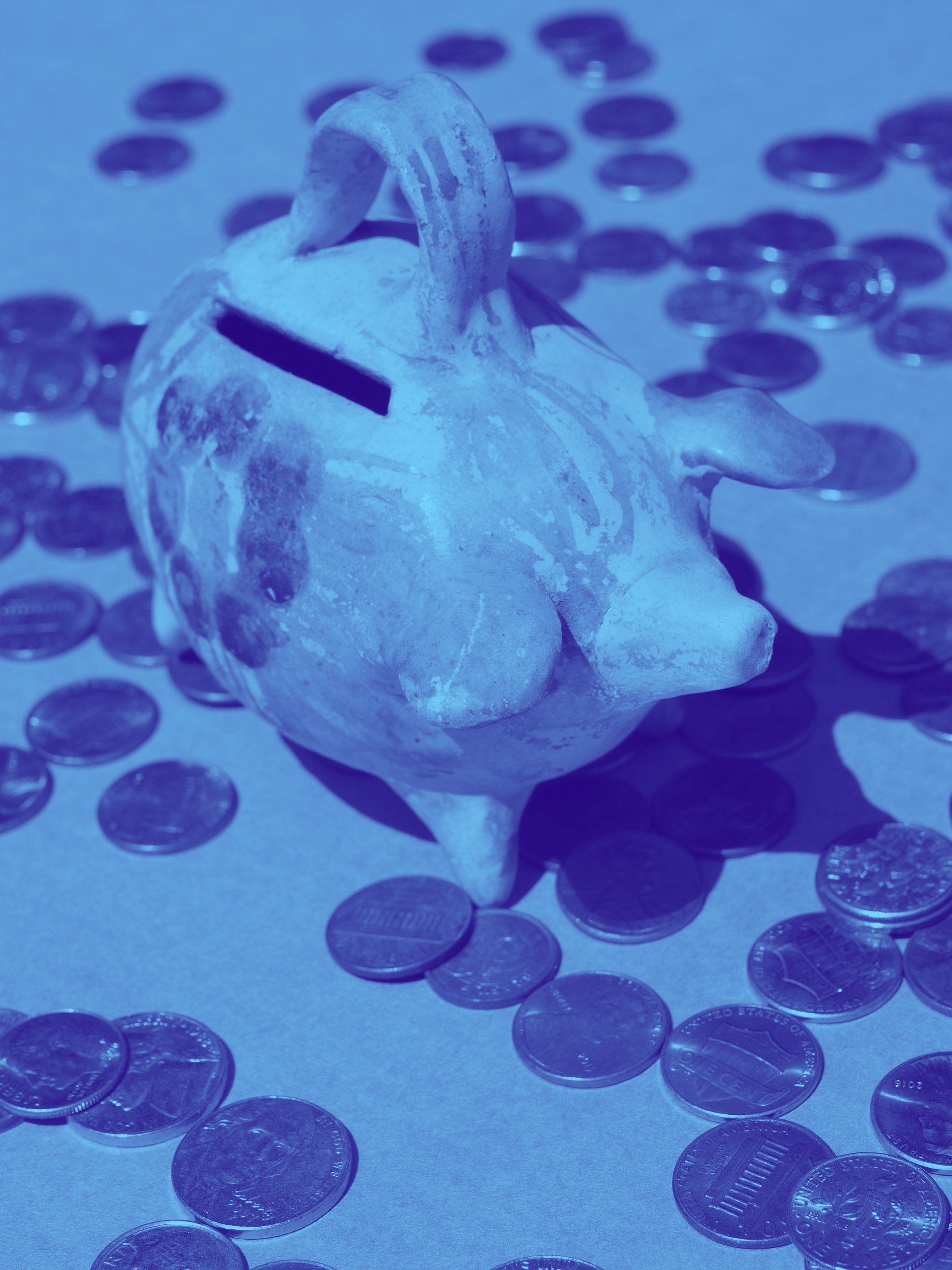 A piggy bank is surrounded by coins on a table
