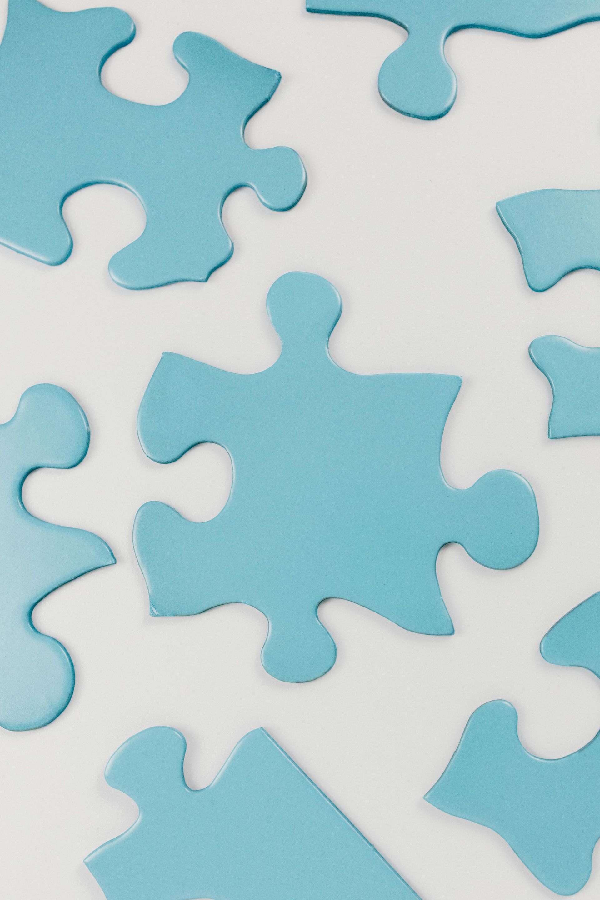 A bunch of blue puzzle pieces are laying on a white surface.