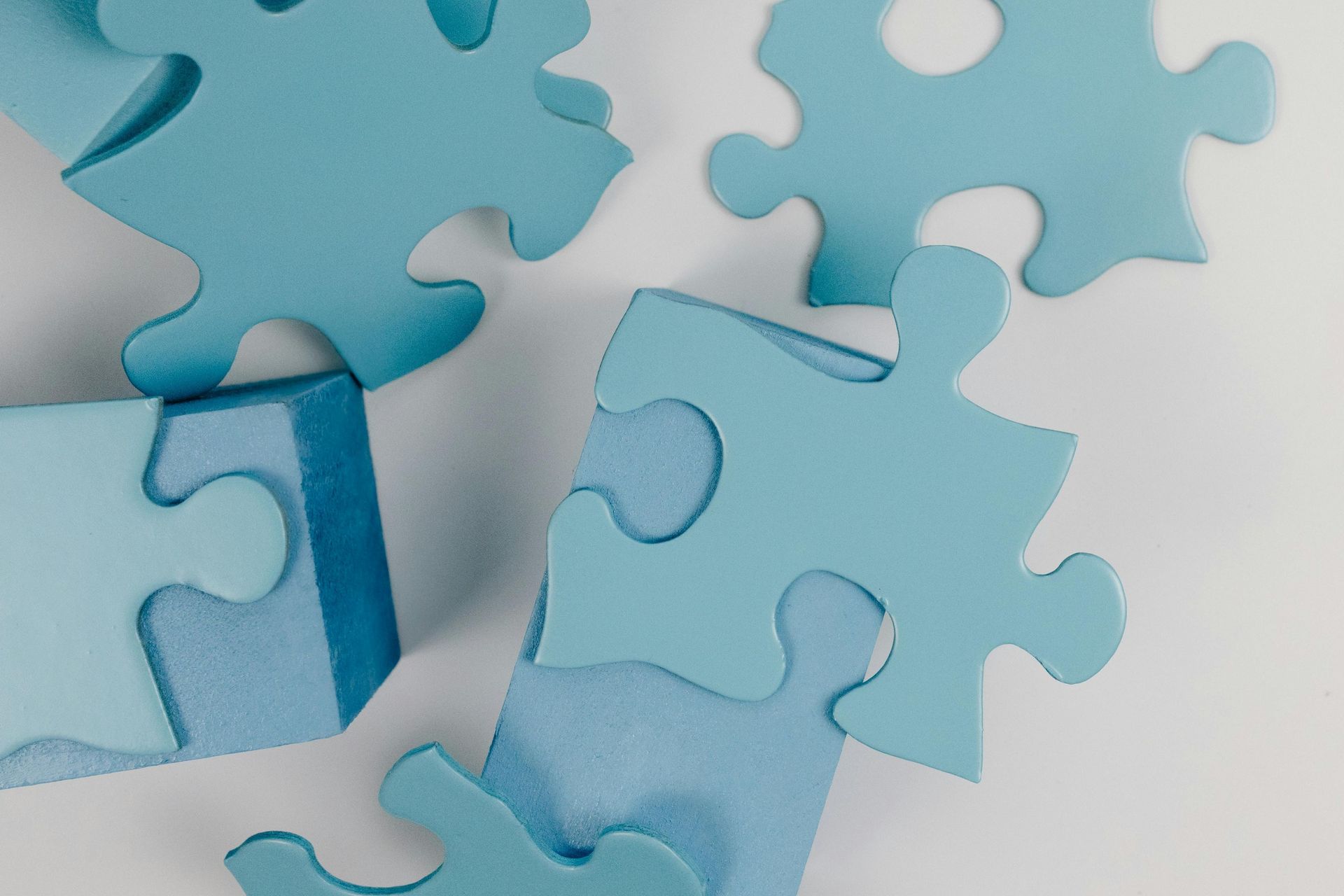 Light blue puzzle pieces scattered on a white surface, some partially connected.