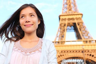 Woman smiling in front of the Eiffel Tower, looking upwards with a serene expression.