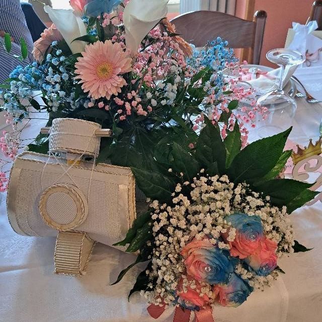 Un tavolo con fiori e una macchina fotografica sopra