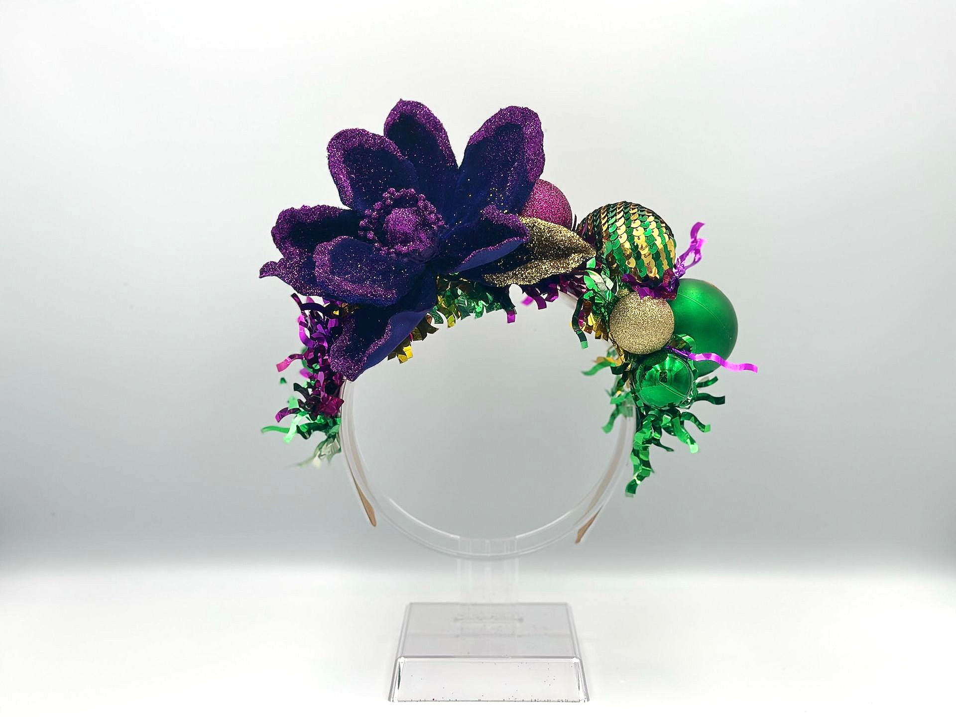 Purple and green Mardi Gras headband with flower, beads, and tinsel.